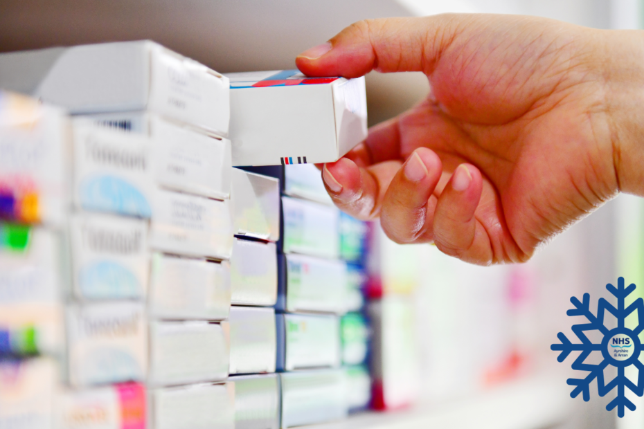 Hand reaching onto a shelf containing boxes of medicine