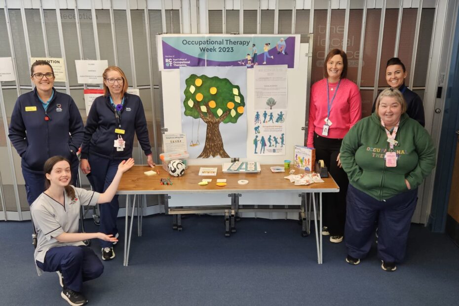 The staff from Children and Young People's Occupational Therapy Team in East Ayrshire standing around a table with a picture of the Forever Tree in the centre.